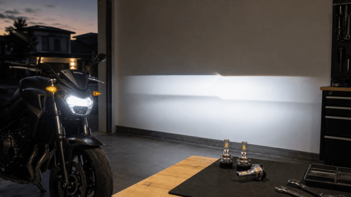 Motorcycle LED headlight beam pattern with replacement bulbs on a garage workbench